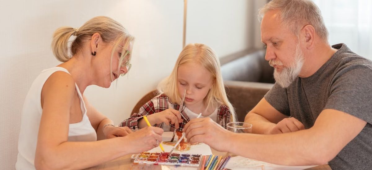 A family of three enjoying creative time with painting and drawing at home.