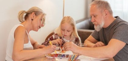 A family of three enjoying creative time with painting and drawing at home.