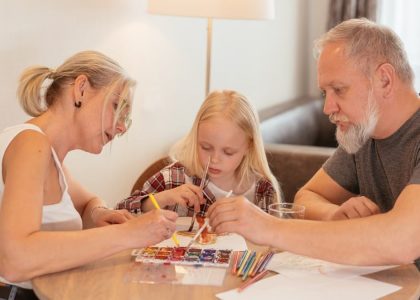 A family of three enjoying creative time with painting and drawing at home.